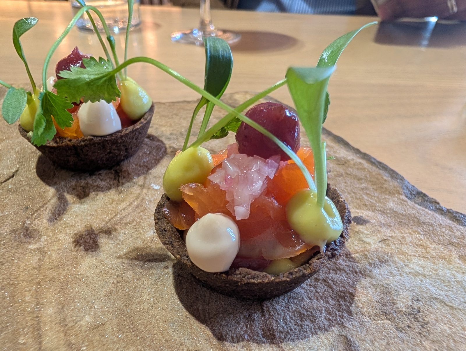 Snacks to start: a tart of cured fish and herbs on a slab of bark.