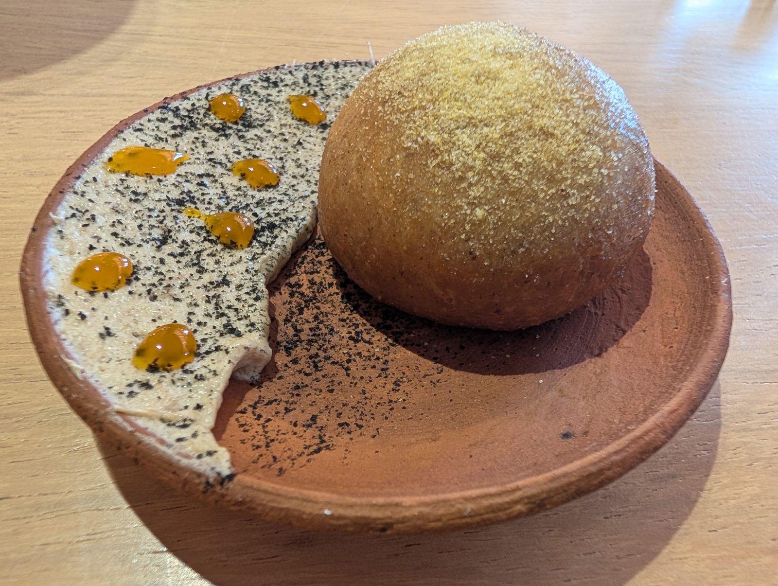 A fried sphere on clay, with two sauces.