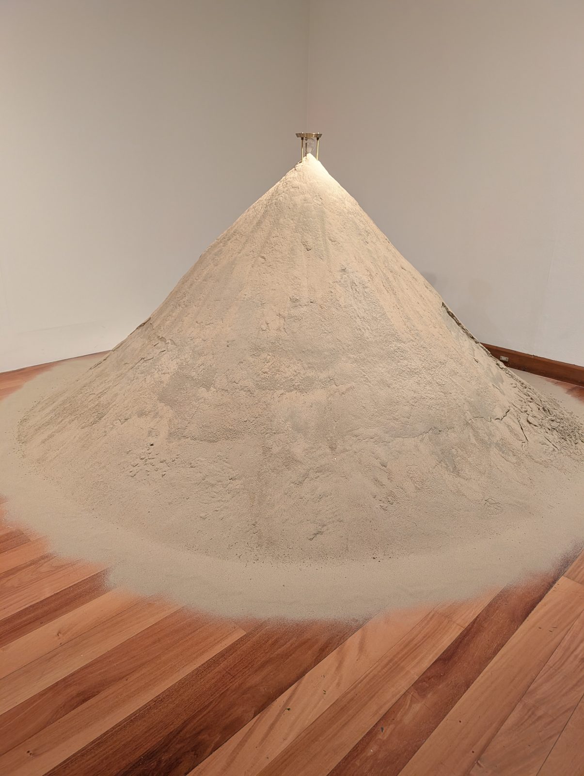 A cone of sand with an hourglass on top, still running.