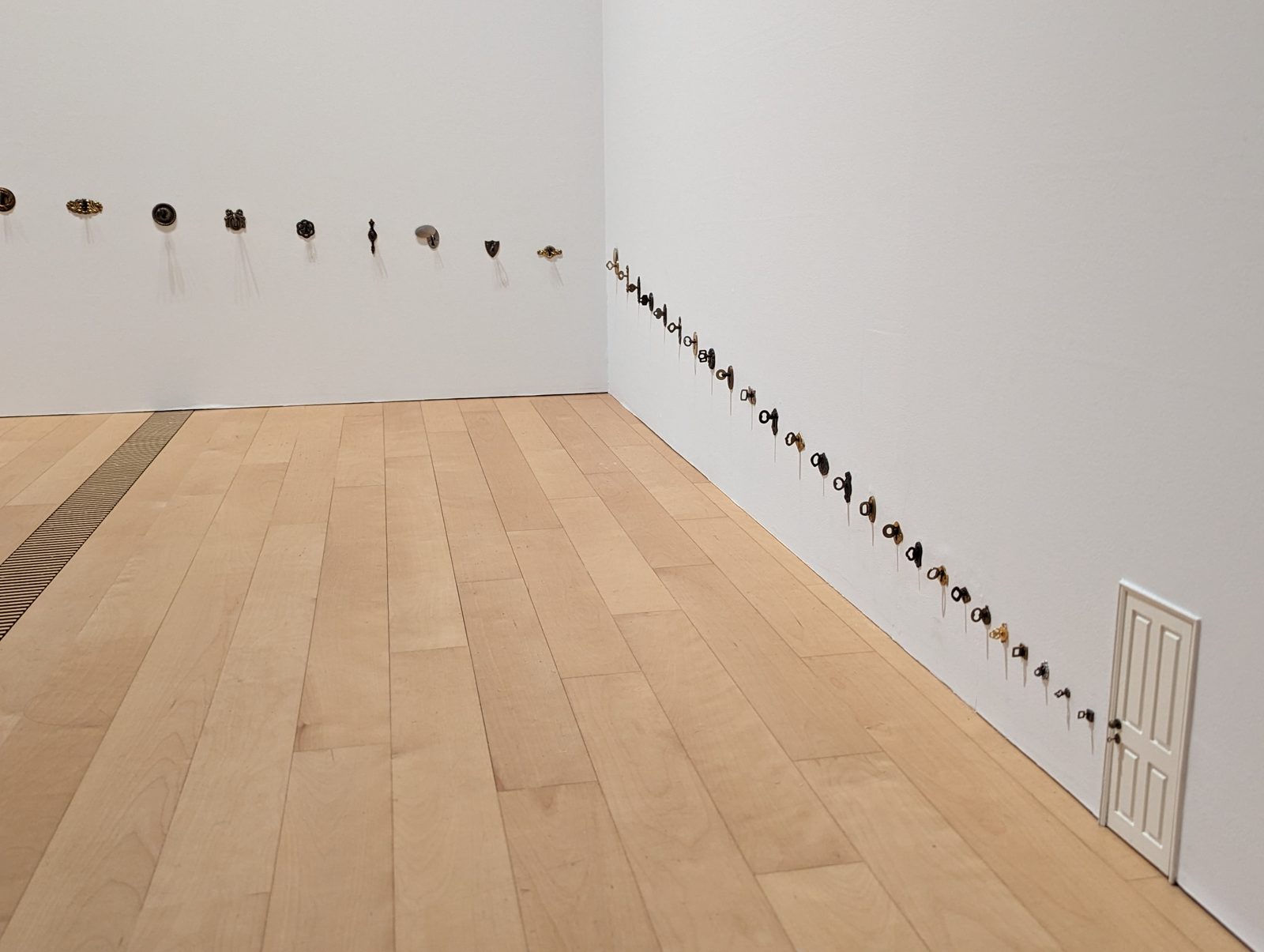 Pola Museum. A row of tiny objects, the whole length of a white wall.